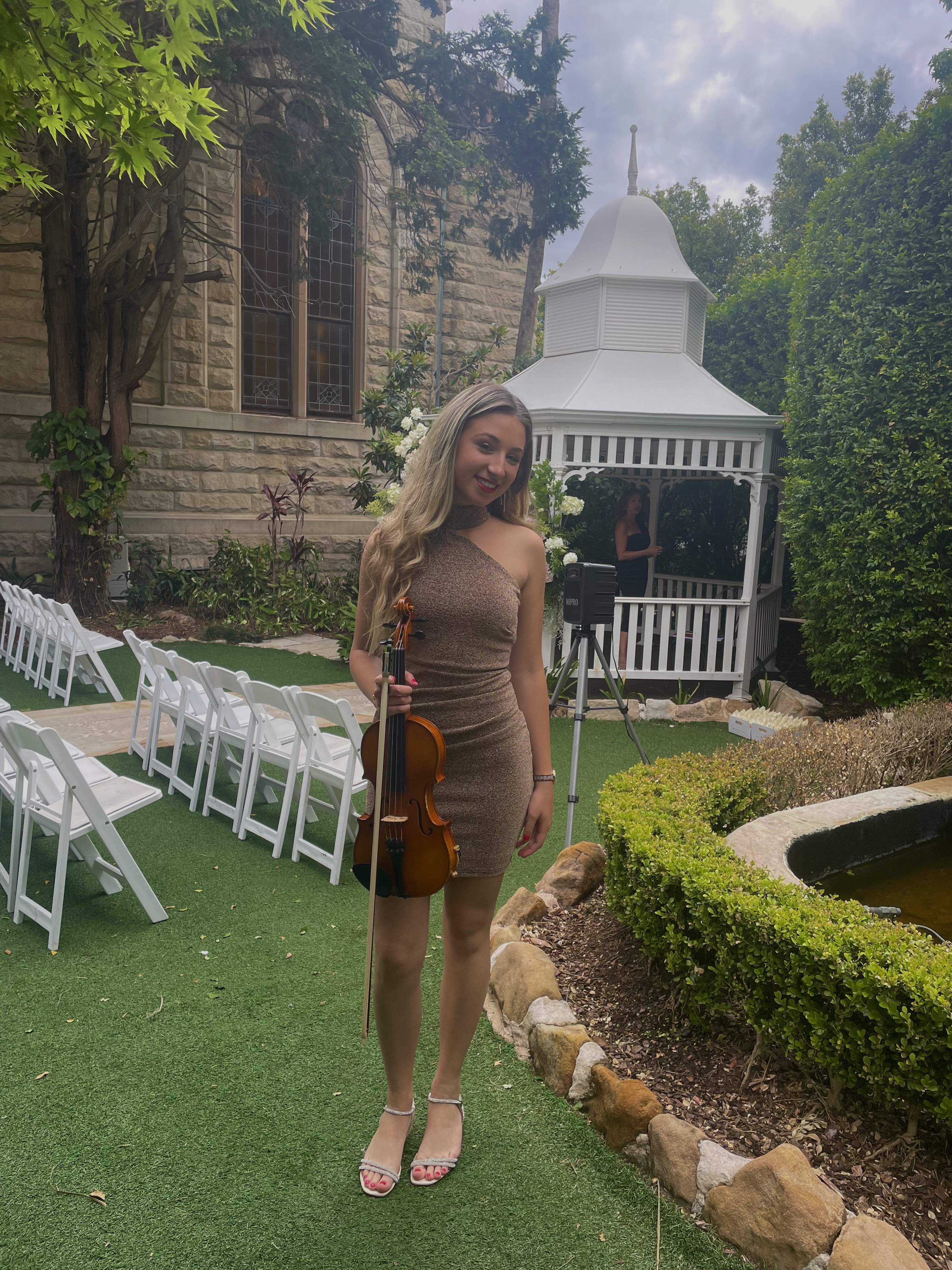 Tali holding violin in a cocktail garden